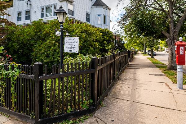 a black fence and a sign next to a sidewalk