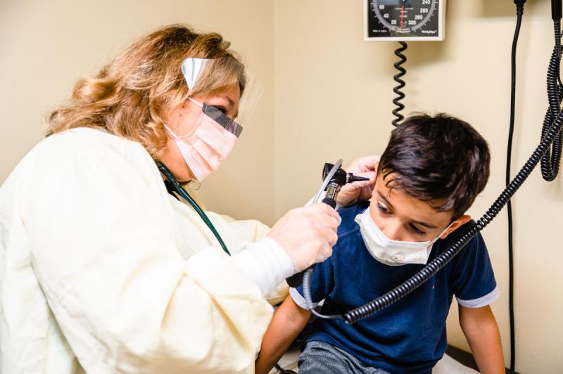 a medical provider examining the ear of a boy