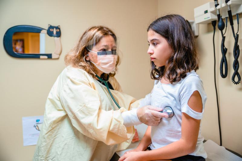 a medical provider listening to a young girls heart