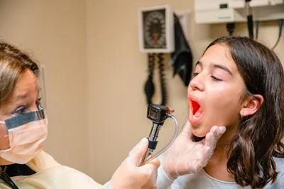 a young girl getting her throat examined